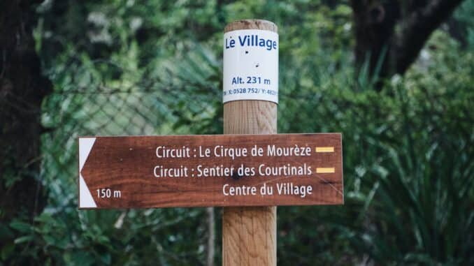 Wooden signpost in forest guiding to Le Cirque de Mourèze and Sentier des Courtinals.