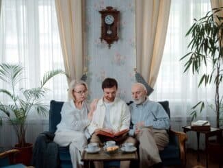 Elderly couple with son enjoying a photo album at home, sharing memories.
