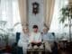 Elderly couple with son enjoying a photo album at home, sharing memories.