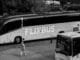 A monochrome photo of FlixBus parked at station with people nearby.