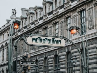 Paris Métro entrance with iconic art nouveau design in front of historic architecture.