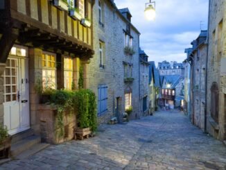 Explore the illuminated cobblestone streets of historic Dinan, Brittany at dusk.