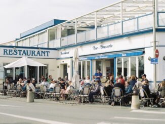 People enjoying a sunny day at a bustling outdoor restaurant in France.