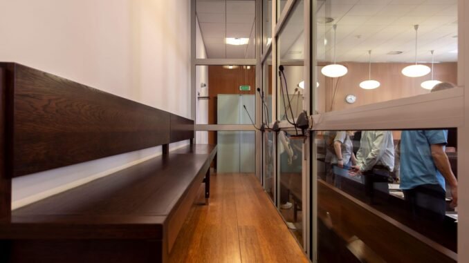 Interior view of a courtroom in Wrocław, Poland, featuring wooden benches and glass partitions.