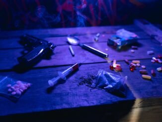A moody scene displaying drugs, a gun, and smoke under dramatic lighting.