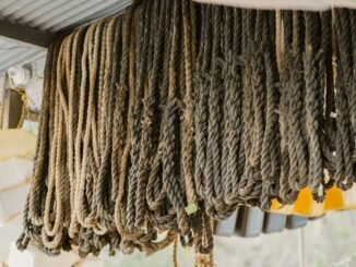 Close-up of various ropes hanging from the ceiling in an outdoor storage area.