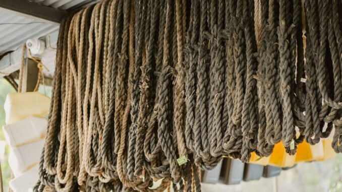Close-up of various ropes hanging from the ceiling in an outdoor storage area.