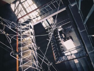 Aerial view of an industrial stairwell with intricate cable arrangement and dramatic shadows.