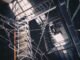Aerial view of an industrial stairwell with intricate cable arrangement and dramatic shadows.