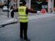 Back view of a crossing guard holding a stop sign in a busy city street.