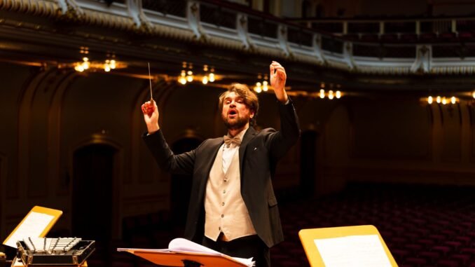 Orchestra conductor passionately leading a performance in an elegant concert hall.