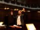 Orchestra conductor passionately leading a performance in an elegant concert hall.