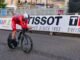 Cyclist in red competing in a race in Harrogate, England, showcasing speed and determination.